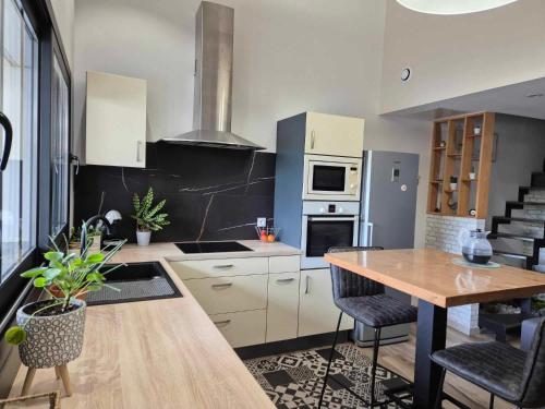 a kitchen with white cabinets and a wooden table at Maisonnette cosy proche de La Rochelle et de L'Ile de Ré in Saint-Xandre