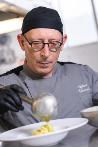 a man is stirring a bowl of food with a spoon at Hotel Mioni Royal San in Montegrotto Terme