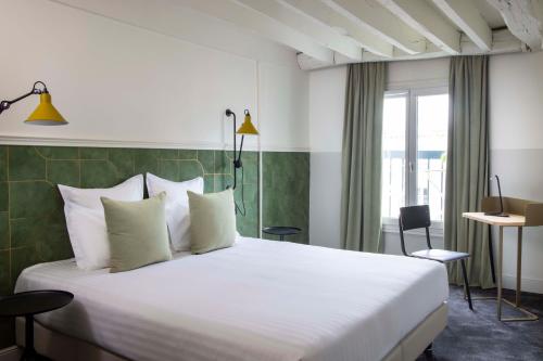 um quarto de hotel com uma cama grande com almofadas brancas em Hôtel Des Mines em Paris