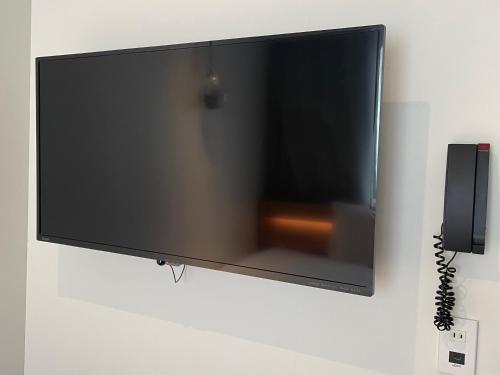 una TV a schermo piatto appesa a un muro di REF Omiya by VESSEL HOTELS a Saitama