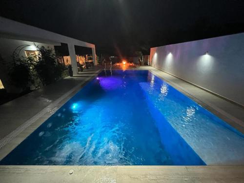 a swimming pool at night with blue water at TREND - cazare, gradina, piscina in Arad
