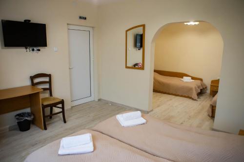 a room with a bed and a desk and a television at Avenue House in Kazanlŭk