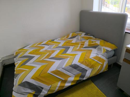 a bedroom with a bed with a yellow and grey comforter at Guest House Bungalow in Walsall