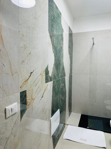 eine Glasdusche in einem Badezimmer mit Marmorwand in der Unterkunft Mandarin Apulia 19 in Bari