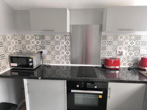 a kitchen with a counter with a toaster and a microwave at Guest House Bungalow in Walsall