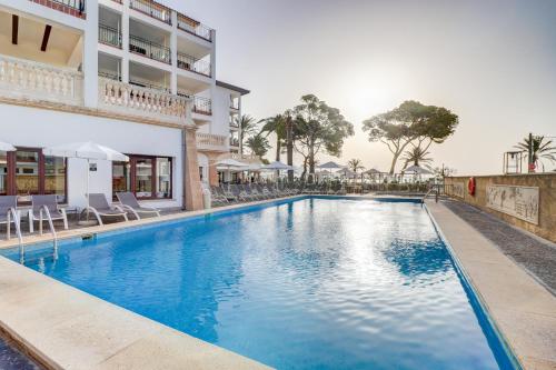 a swimming pool with chairs and a building at Hoposa Uyal in Port de Pollensa