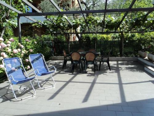 un patio con mesa y sillas en un jardín en Appartamenti Villa Adriana Torbole, en Nago-Torbole