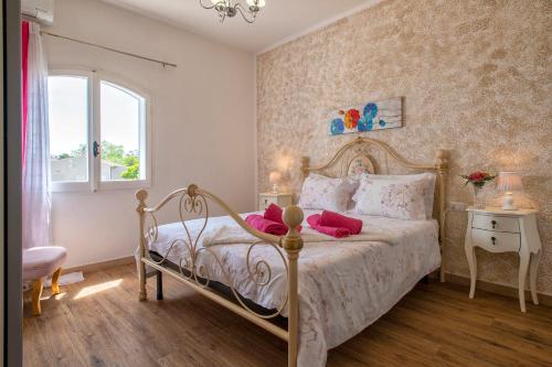 a bedroom with a bed with pink pillows and a window at Villa Sara in Sorso