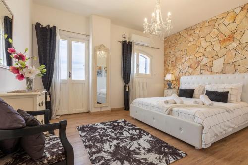 a bedroom with a white bed and a stone wall at Villa Sara in Sorso