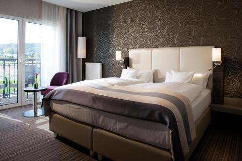 a hotel room with a large bed and a window at Vital Hotel Rhein Main Therme Wellness Resort & SPA in Hofheim am Taunus