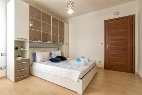 a bedroom with a bed with white sheets and blue pillows at Villa Felicità in Sorso