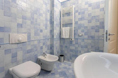 La salle de bains est pourvue de carrelage bleu, de toilettes et d'un lavabo. dans l'établissement Bilocale Corso Italia 697 2° piano con balcone, à Gallipoli