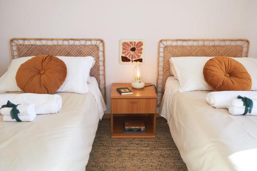 two beds with white sheets and a wooden night stand at Marzamemi Porto in Marzamemi