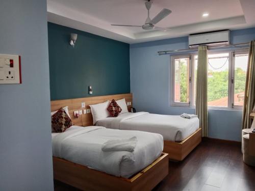 twee bedden in een kamer met blauwe muren bij Diyalo Foodland Chitwan in Bharatpur