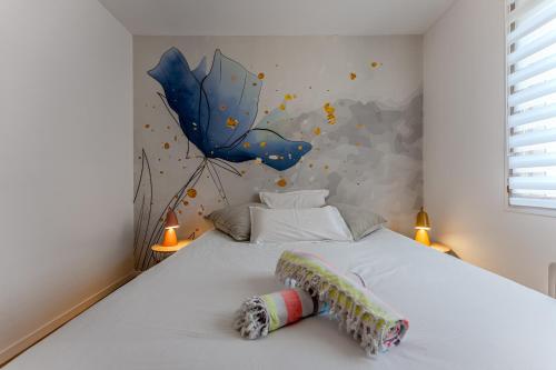 - une chambre avec un lit blanc et un parasol bleu sur le mur dans l'établissement La Farniente, à Grayan-et-lʼHôpital