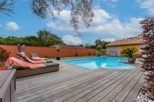 une cour arrière avec une piscine et une terrasse en bois dans l'établissement La Farniente, à Grayan-et-lʼHôpital