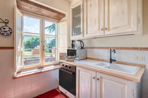 uma cozinha com armários brancos, um lavatório e uma janela em Villa Nobile Oasi em Porcari