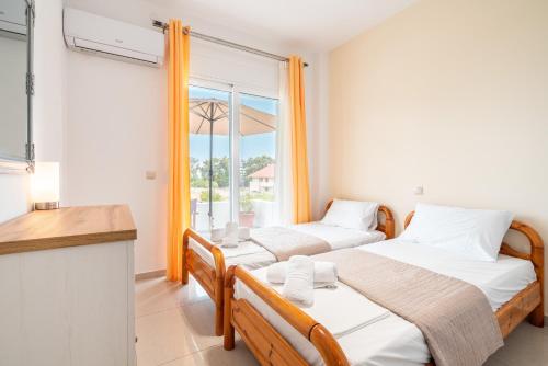 two beds in a room with a window at Ilia's Apartment with view 2 in Asgourou