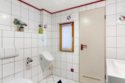 La salle de bains est pourvue de carrelage blanc, de toilettes et d'un lavabo. dans l'établissement Ferienwohnung Faisst, à Kappel-Grafenhausen