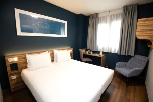 Pokój hotelowy z łóżkiem i krzesłem w obiekcie Travelodge Madrid Metropolitano w Madrycie