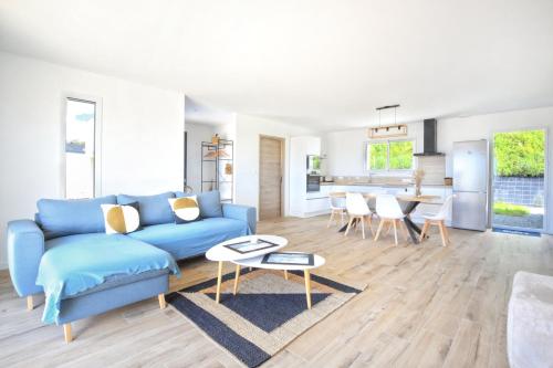 un salon avec un canapé bleu et une table dans l'établissement Les Euphorbes - Charmante maison avec vue mer, à Saint-Georges-de-la-Rivière
