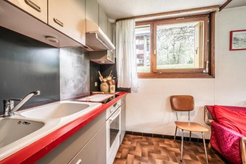 uma pequena cozinha com um lavatório e uma janela em Appartement en residence em Morzine