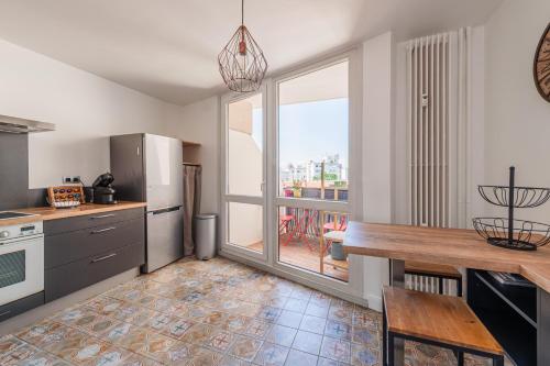 une cuisine avec une table et une grande fenêtre dans l'établissement L'Abri de la Krutenau - charmant Triplex, à Strasbourg