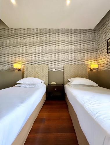 two beds sitting next to each other in a room at Hotel Restaurant Christophe Colomb in Calvi