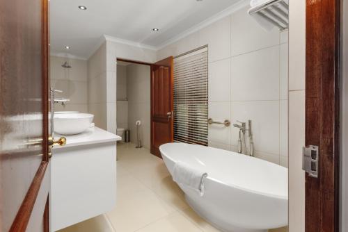 Aaldering Luxury Lodges في ستيلينبوش: حمام أبيض مع حوض ومغسلة