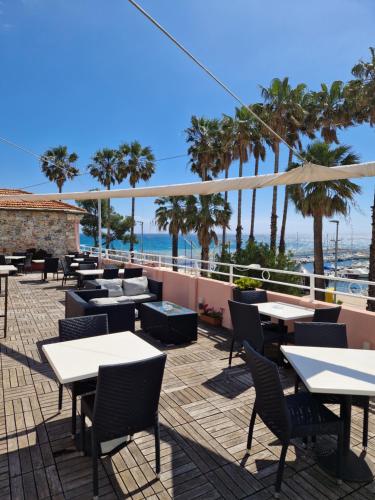 a patio with tables and chairs and the ocean at Vela Bianca H & R in Diano Marina