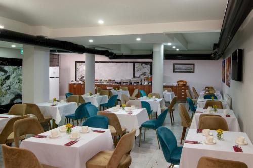 un restaurante con mesas blancas y sillas azules en İstanbul Efes Hotel en Estambul