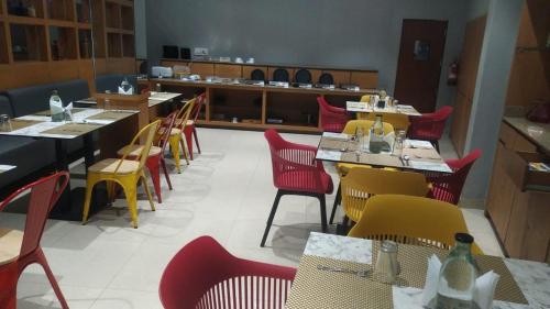 a restaurant with red and yellow chairs and tables at Sparrow Hotel Managed by Siara Sariska Alwar in Alwar