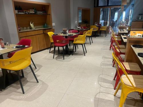 a dining room with tables and yellow chairs at Sparrow Hotel Managed by Siara Sariska Alwar in Alwar