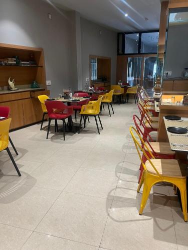 a dining room with tables and yellow chairs at Sparrow Hotel Managed by Siara Sariska Alwar in Alwar