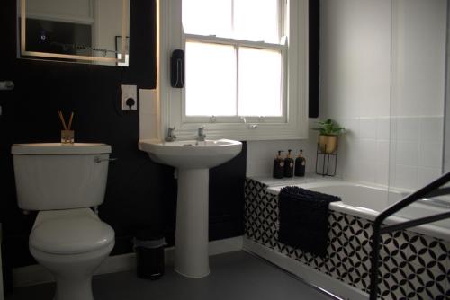 a bathroom with a toilet and a sink and a tub at Top Spot 2-Bed Apartment Town Centre Train Station Wi-Fi in Colchester