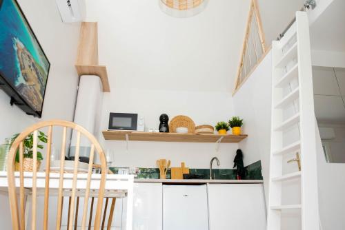 une cuisine avec des armoires blanches et une table et des chaises dans l'établissement La Maisonnette Marloise, à Marles-en-Brie