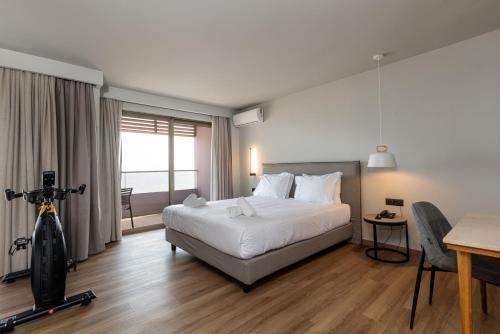 a hotel room with a bed and a table and a desk at Iolida Beach by Smile Hotels in Agia Marina Nea Kydonias
