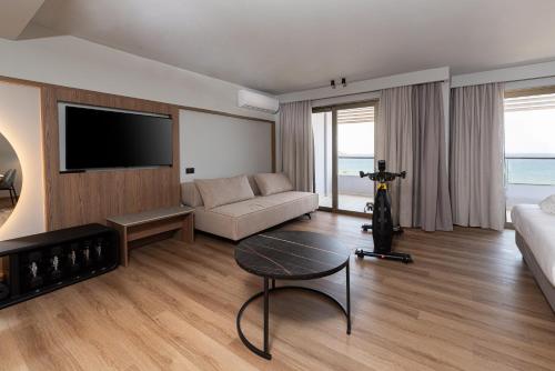 a living room with a couch and a table at Iolida Beach by Smile Hotels in Agia Marina Nea Kydonias