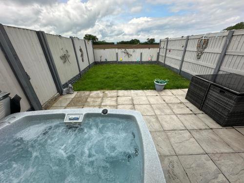a hot tub in a backyard with a fence at Dwylig Isa Holiday Cottages in Rhuddlan
