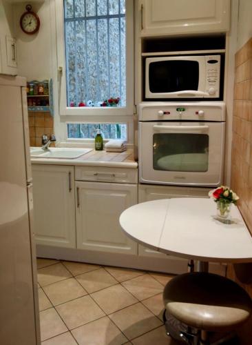 - une cuisine blanche avec une table et un four micro-ondes dans l'établissement 55 m2 apartment very quiet close to the Eiffel Tower, à Paris