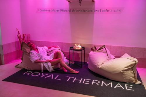 a woman laying on a couch in a room with pink lighting at Hotel Mioni Royal San in Montegrotto Terme