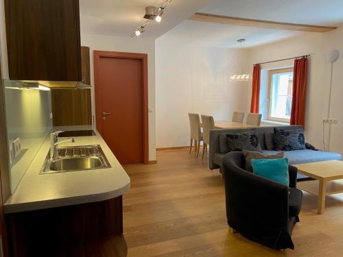 uma cozinha e sala de estar com um lavatório e um sofá em Gasthof Kronburg em Zams