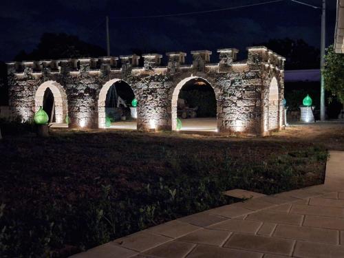 een stenen muur met lichtjes in een park 's nachts bij B&B Lu Core Nosciu in Aradeo