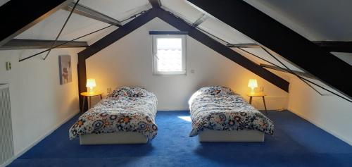 a attic room with two beds and two lamps at Wellness huisje "Celebration" in Balkbrug