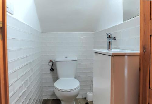 Baño blanco con aseo y lavamanos en Casa Sabelín en Suesa