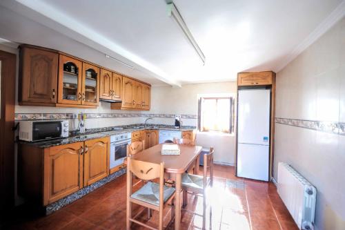 a kitchen with wooden cabinets and a table and a refrigerator at Casa Sabelín in Suesa