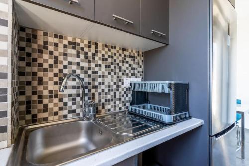 a kitchen counter with a sink and a microwave at Maryam's 2-BR Apt Facing Larnaca Harbor W/ Pool in Larnaka