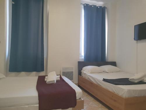 2 letti in una camera con tende blu di Hotel Du Centre a Marsiglia