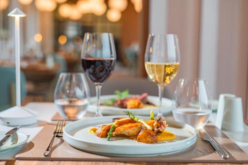 a table with two plates of food and wine glasses at Best Western Premier Malta in St Paul's Bay