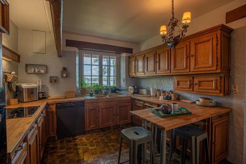 une cuisine avec des placards en bois et une table avec des tabourets dans l'établissement Le Manoir de Saint Brendan, à Baden